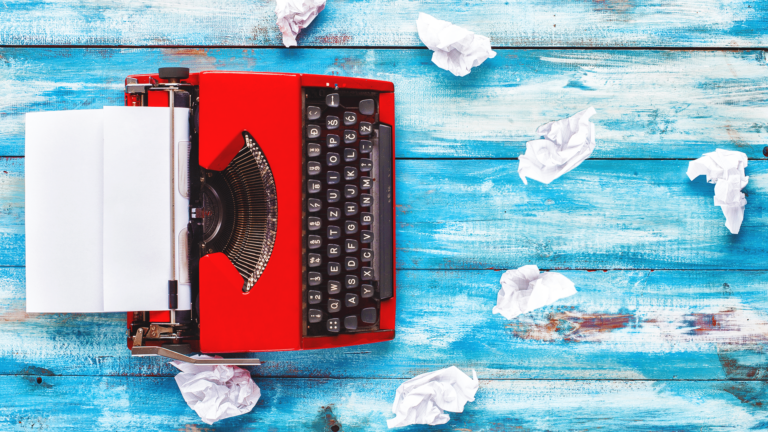 A table painted like a sky holds a red typewriter to intro, What is brand journalism?