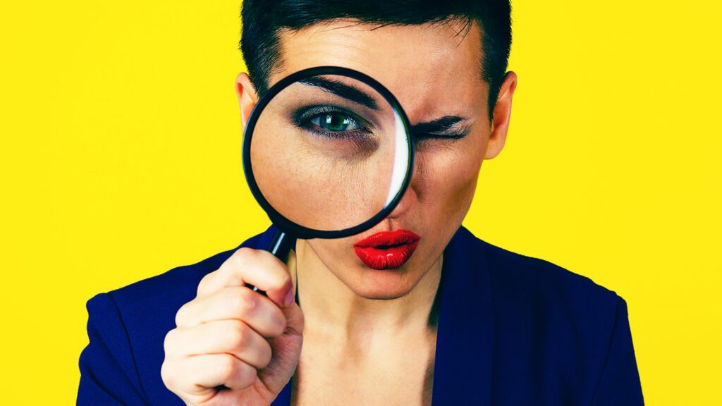 Business woman looks you over with a magnifying glass and introduces our blog, Contrary to Reports: What Facebook REALLY Did About 'Jew Hater' Targeting