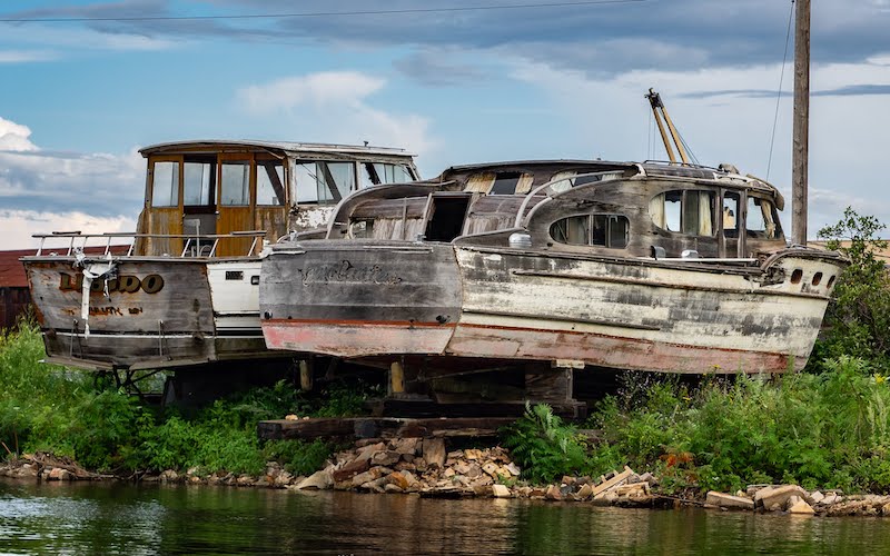 Two old all-wood cabin cruiser boats sit in dry dock.